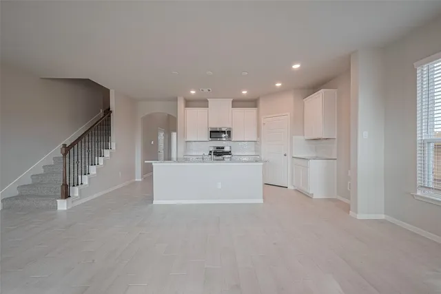 a view of a kitchen with refrigerator and white cabinets