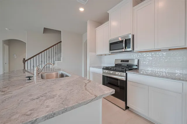 a kitchen with stainless steel appliances granite countertop a stove a sink and a microwave