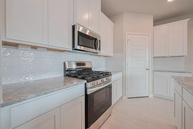 a kitchen with stainless steel appliances granite countertop white cabinets a stove top oven a sink and dishwasher