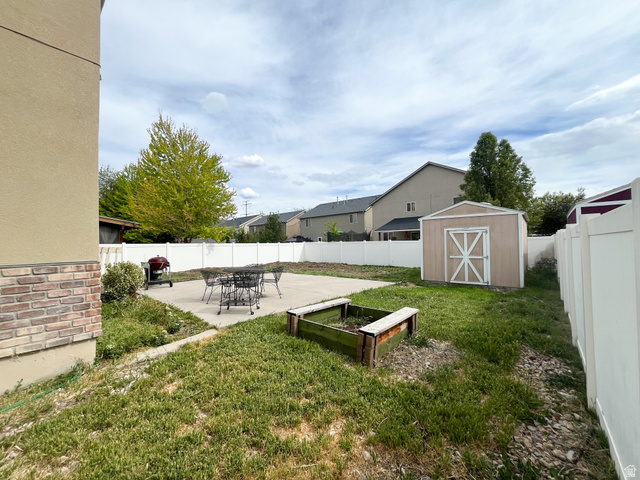 297 West Bricker Road Draper, UT 84020 - Photo 24 of 25 Fenced backyard featuring a patio, a vegetable garden, a shed, and a residential view