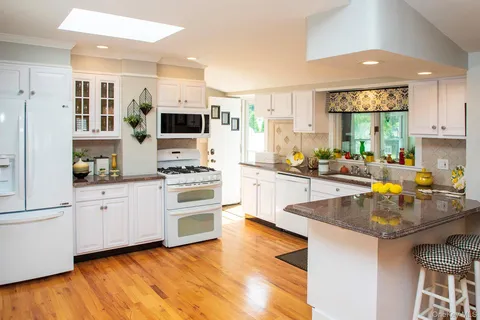 a kitchen with stainless steel appliances granite countertop a stove a sink and a microwave