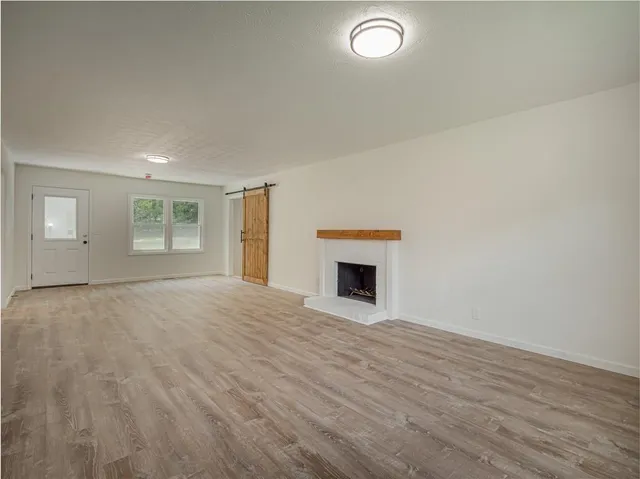an empty room with wooden floor fireplace and windows