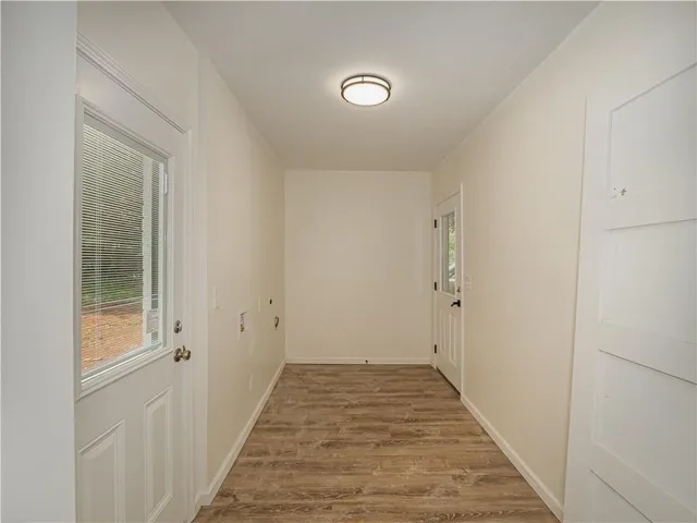 a view of a hallway with wooden floor and a bathroom