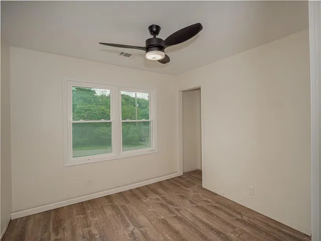 a view of empty room with wooden floor and fan