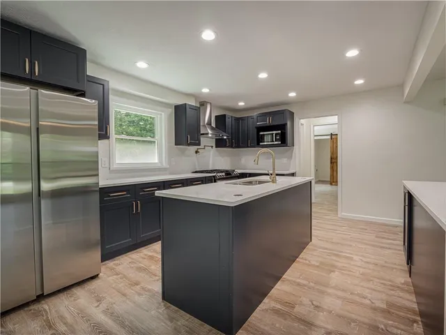 a kitchen with kitchen island stainless steel appliances a sink stove and refrigerator
