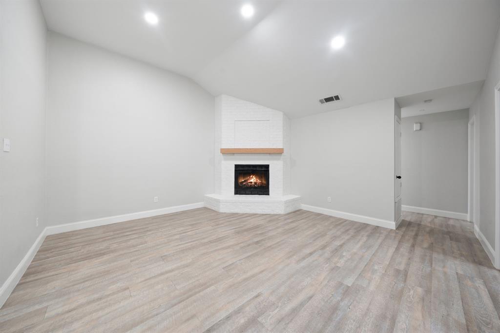 310 Valley Spring Drive Arlington, TX 76018 - Photo 9 of 24 Spacious room featuring light wood-finish flooring, a white brick fireplace with a wood mantle, recessed lighting, and white baseboards