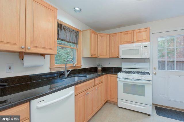 a kitchen with granite countertop white cabinets and white appliances