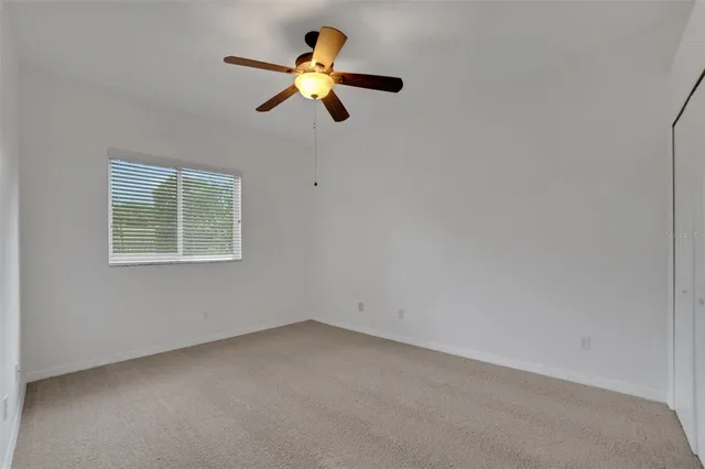 an empty room with a window and a ceiling fan