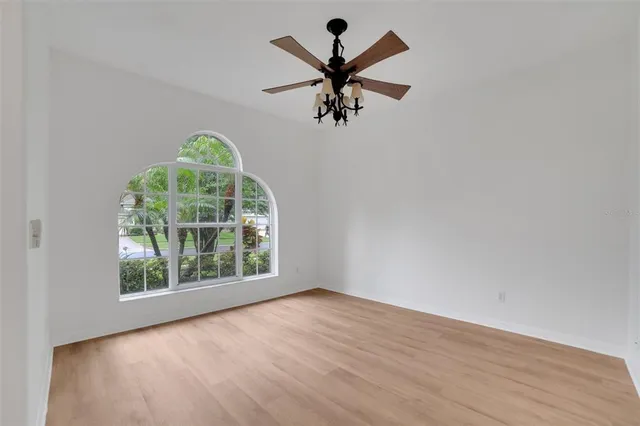 an empty room with windows and ceiling fan