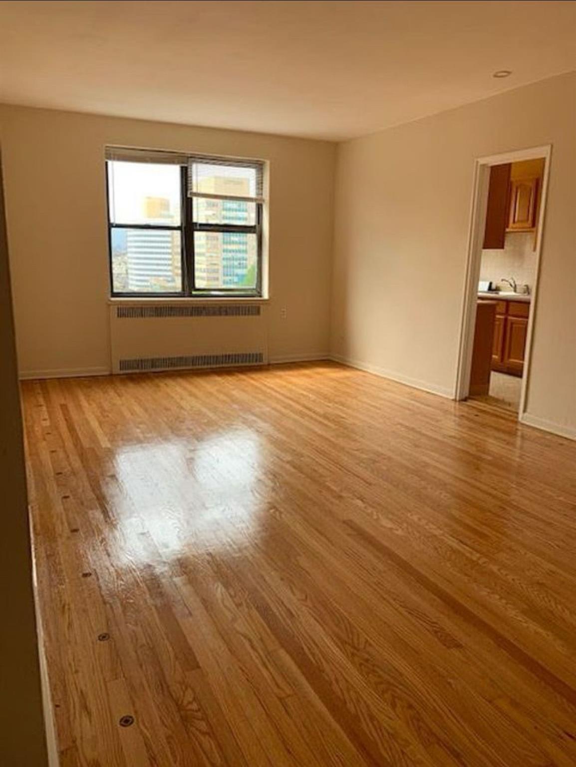 98-76 Queens Boulevard, Unit 6L Queens, NY 11374 - Photo 1 of 5 Empty room with light wood-type flooring and radiator