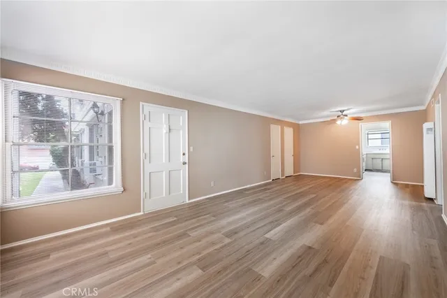 a view of empty room with wooden floor and fan