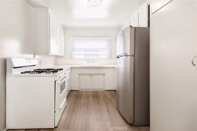 a kitchen with a refrigerator a sink and wooden floor
