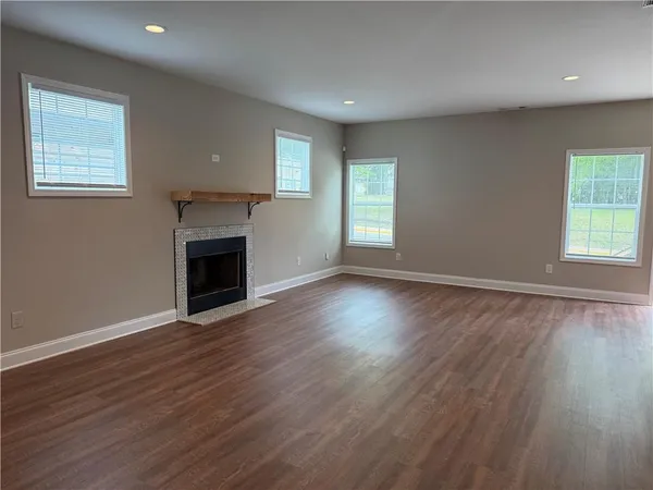 an empty room with wooden floor a fireplace and windows