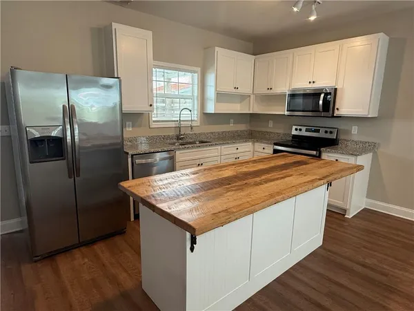 a kitchen with stainless steel appliances granite countertop a refrigerator a sink a stove a microwave and wooden cabinets