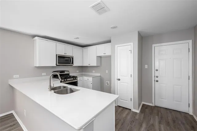 a kitchen with stainless steel appliances a sink a stove a refrigerator and cabinets