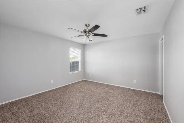 a view of an empty room with a ceiling fan and window