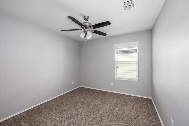 an empty room with a window and a fan