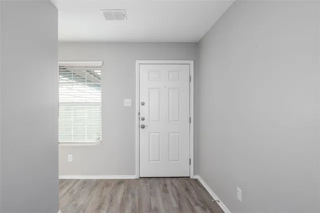an empty room with wooden floor and windows