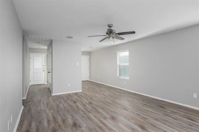 a view of empty room with wooden floor and fan