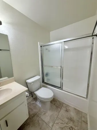 a bathroom with a granite countertop sink toilet and shower