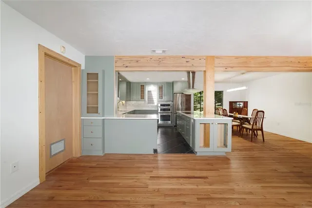 a view of a kitchen with kitchen island a sink wooden floor and living room
