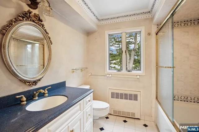 a bathroom with a granite countertop toilet a sink a mirror and a window