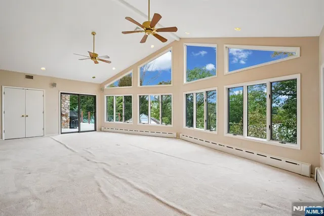 a view of an empty room with a window and ceiling fan
