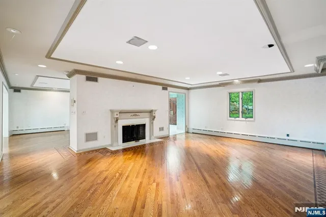 a view of a livingroom with wooden floor a fireplace and windows