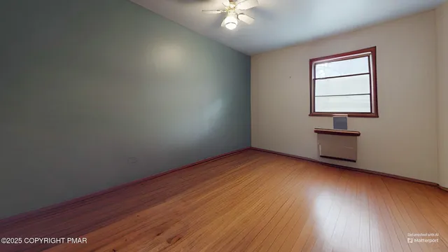 a view of empty room with wooden floor and fan