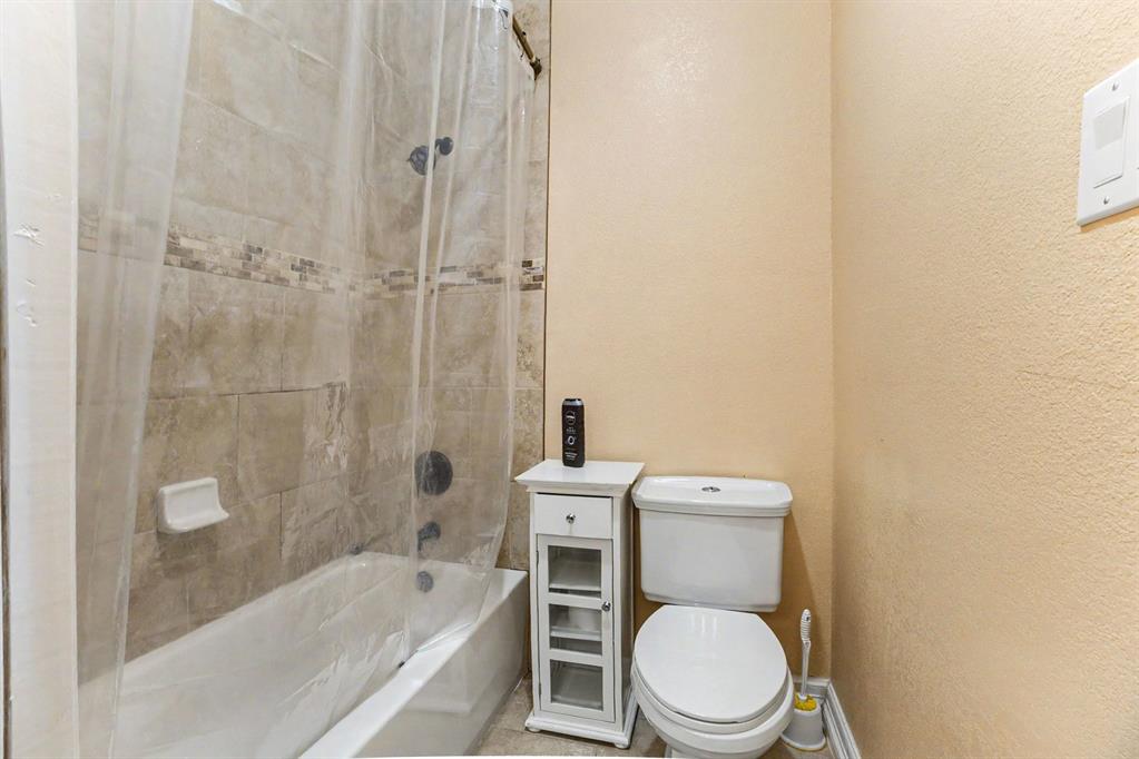 505 South Bluegrove Road Lancaster, TX 75146 - Photo 22 of 37 a white toilet sitting next to a bath tub and a shower