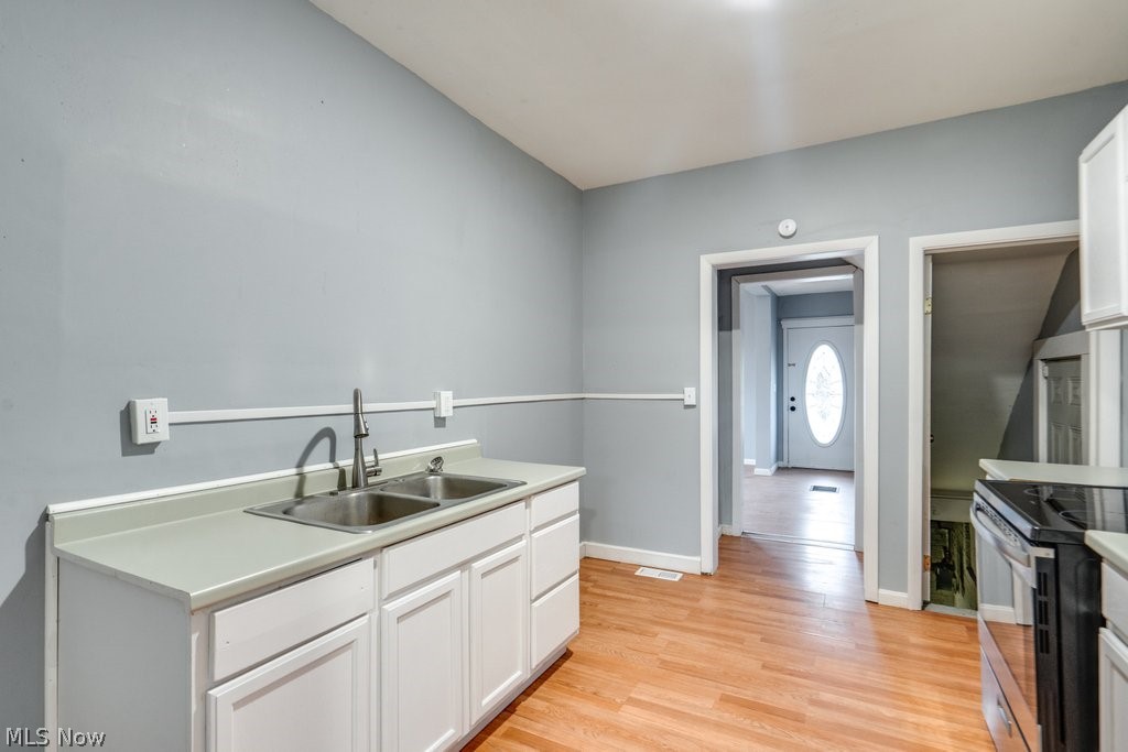 1607 9th Street Southwest Canton, OH 44706 - Photo 20 of 41 Kitchen featuring white cabinetry, light countertops, and a double basin stainless steel sink with a gooseneck faucet