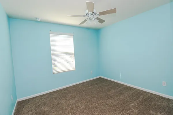 an empty room with a ceiling fan and a window