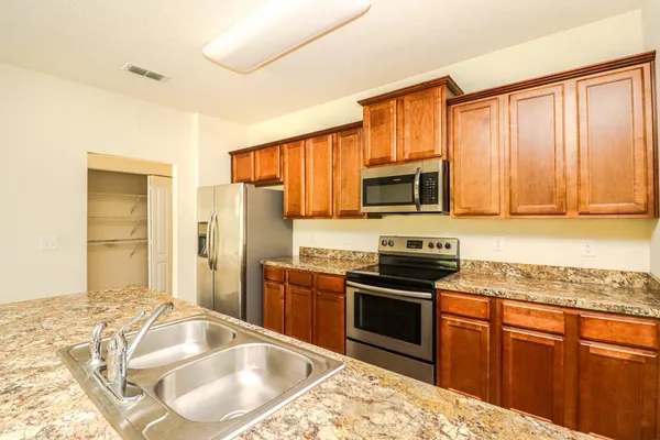 a kitchen with granite countertop a stove sink microwave and refrigerator