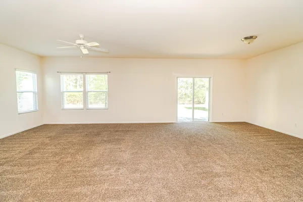 an empty room with windows and chandelier fan