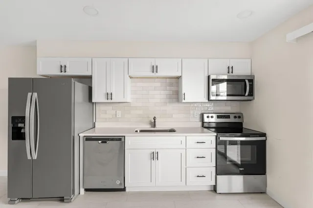 a kitchen with stainless steel appliances white cabinets and a refrigerator