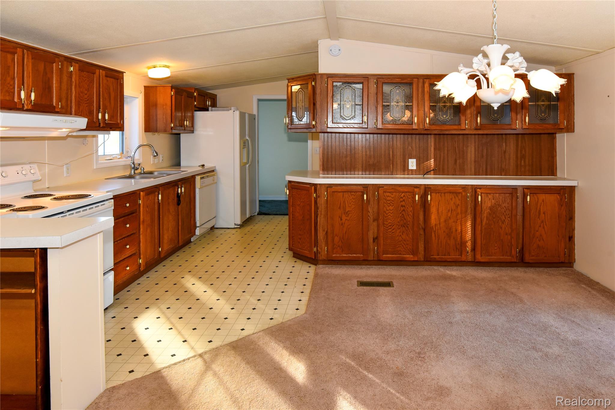 1094 Blamer Road Fairview, MI 48621 - Photo 27 of 97 Kitchen with wood finish cabinets, white appliances, glass insert cabinets, light countertops, and vaulted ceiling
