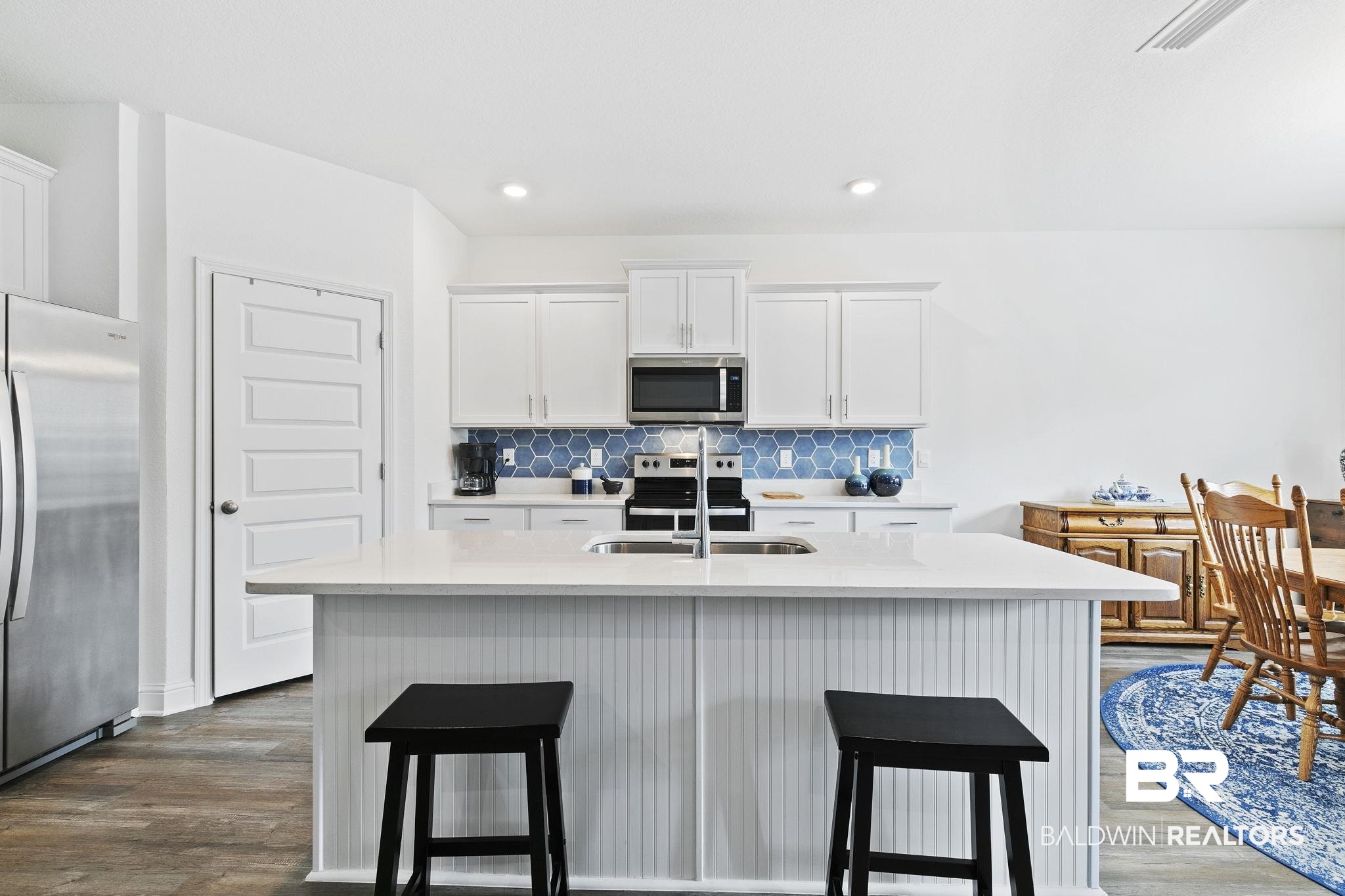 1141 Pencarro Boulevard Foley, AL 36535 - Photo 16 of 70 Kitchen featuring appliances with stainless steel finishes, tasteful backsplash, sink, white cabinets, and a kitchen island with sink