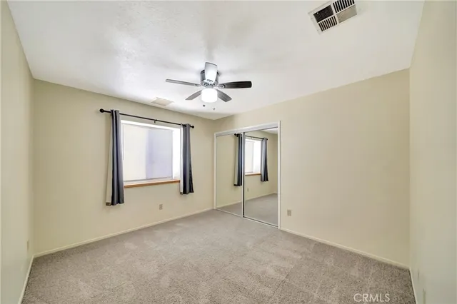 an empty room with windows and fan