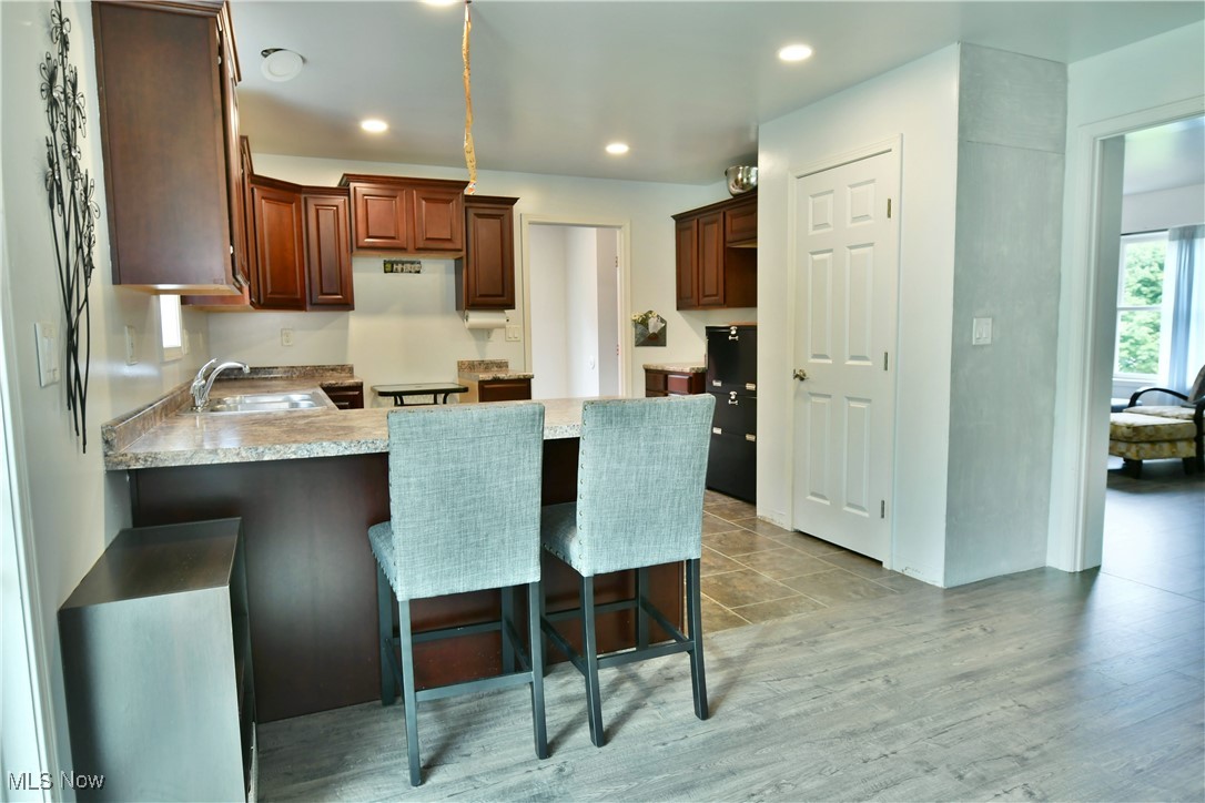 6005 Hurlburt Road Rome, OH 44085 - Photo 14 of 50 Kitchen with a breakfast bar, kitchen peninsula, light hardwood / wood-style floors, and sink