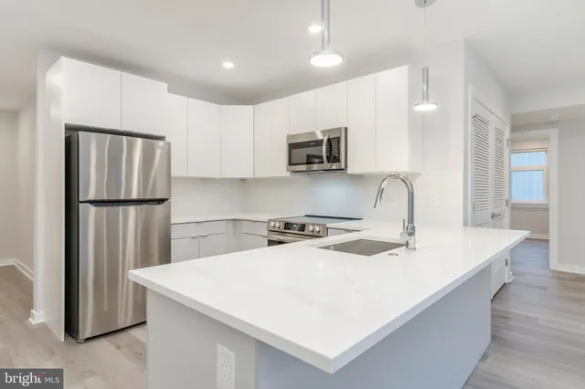 a kitchen that has a sink a refrigerator and a stove top oven