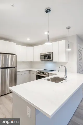 a kitchen with stainless steel appliances granite countertop a sink a stove a refrigerator a center island a stove and white cabinets