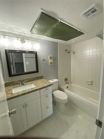 a bathroom with a granite countertop sink a toilet a mirror and shower