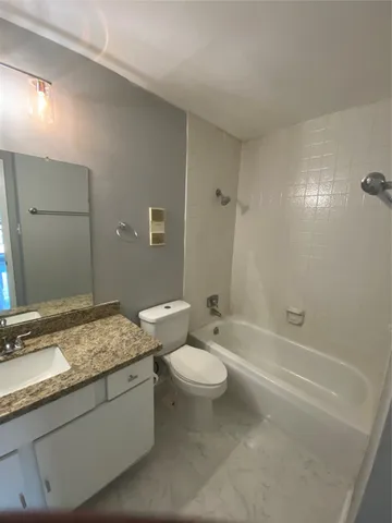 a bathroom with a granite countertop sink a toilet a mirror and shower