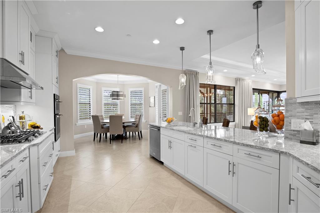 16391 Viansa Way, Unit 101 Naples, FL 34110 - Photo 18 of 48 a large white kitchen with lots of counter space and chandelier
