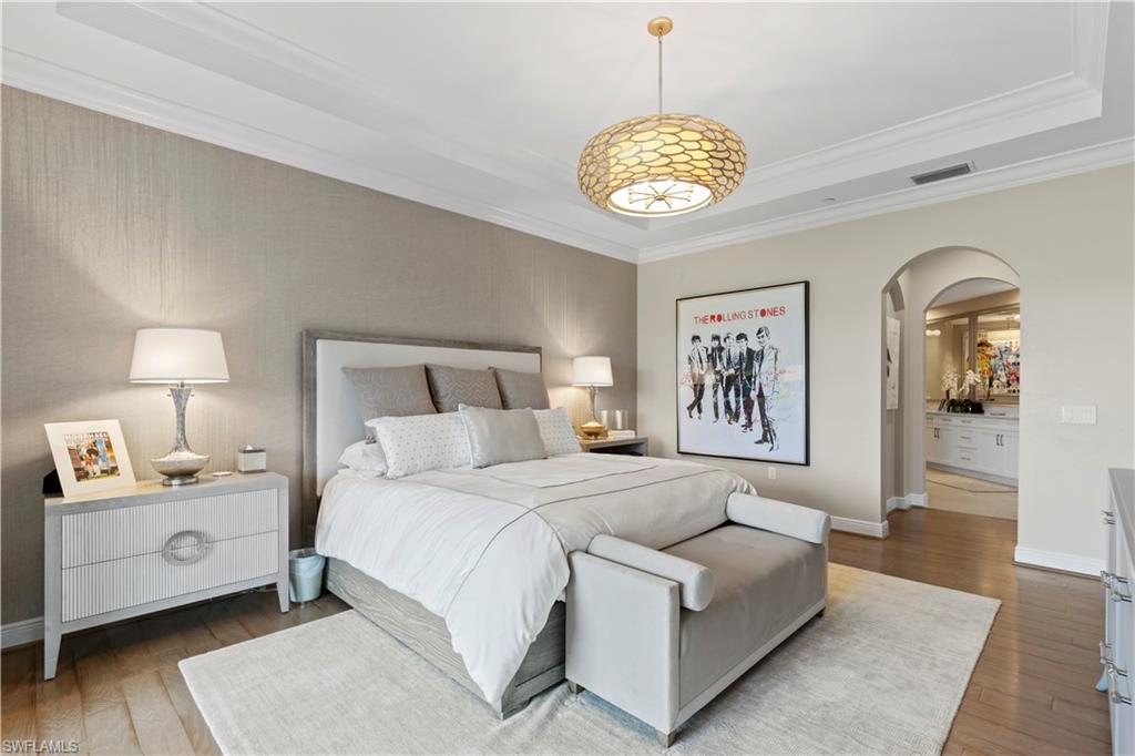 16391 Viansa Way, Unit 101 Naples, FL 34110 - Photo 31 of 48 a spacious bedroom with a bed and a chandelier