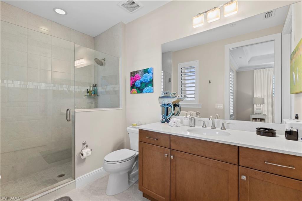 16391 Viansa Way, Unit 101 Naples, FL 34110 - Photo 38 of 48 a bathroom with a toilet sink vanity and mirror