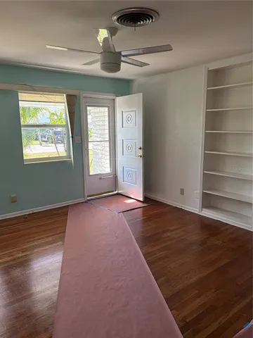 an empty room with wooden floor and windows