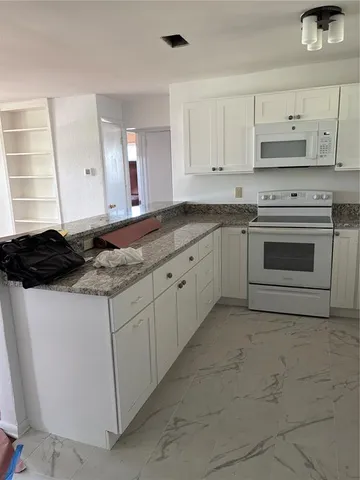 a kitchen with granite countertop white cabinets and appliances