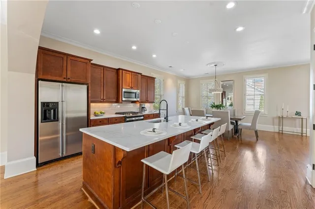 a kitchen with stainless steel appliances granite countertop a stove a sink dishwasher and a refrigerator with wooden floor