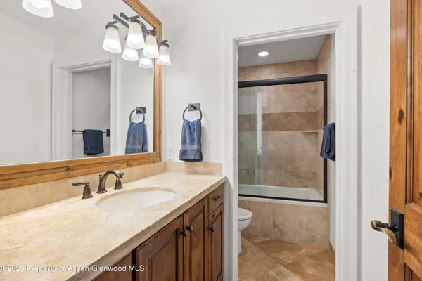 a bathroom with a granite countertop sink a toilet a mirror and shower